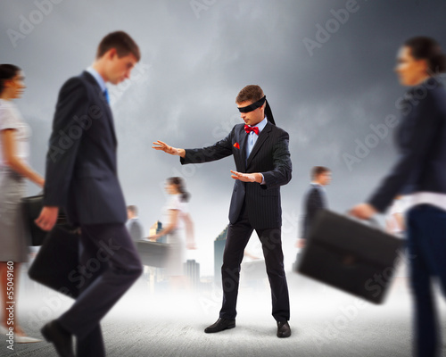 Businessman in blindfold among group of people photo