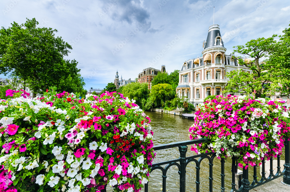 Naklejka premium Canal in Amsterdam with flowers on a bridge
