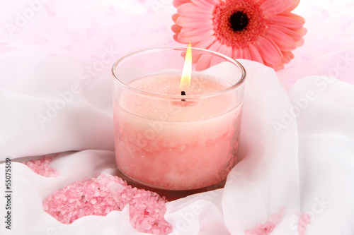 Beautiful candle with flower on white cloth  close up
