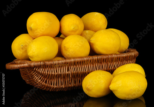 Ripe lemons in wicker basket isolated on black