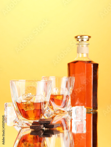 Bottle and two glasses of scotch whiskey, on color background