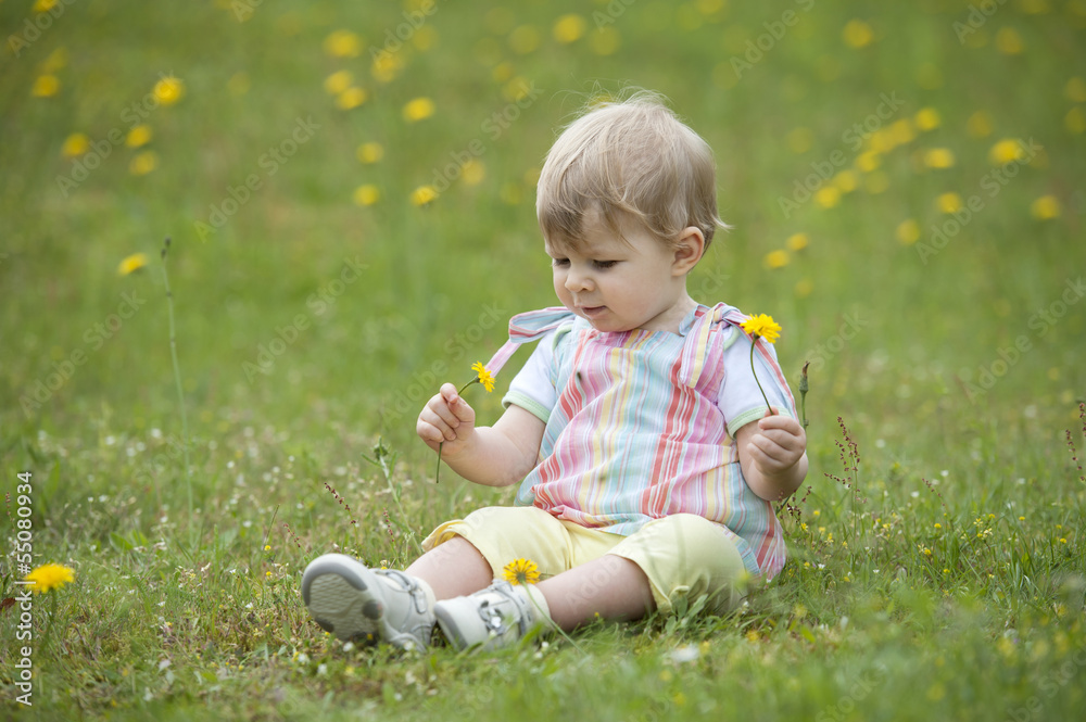 toddler seated in the garden , playing with flowers toddler seated in the garden , playing with flowers