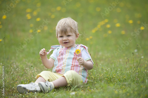 toddler seated in the garden , playing with flowers