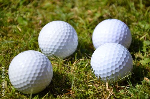Four white golf balls in the ruff