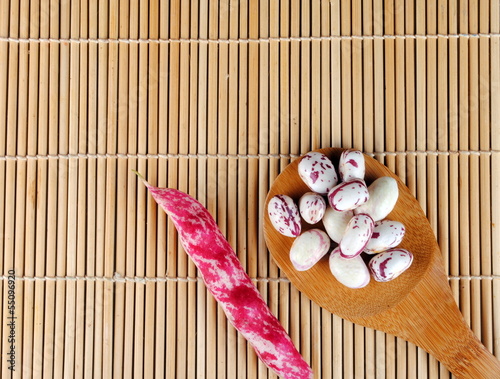 purple beans over a spoon on a bamboo placemat
