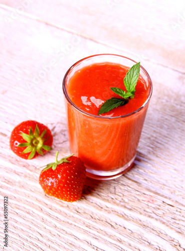 Strawberry smoothie in glass with mint and two berries