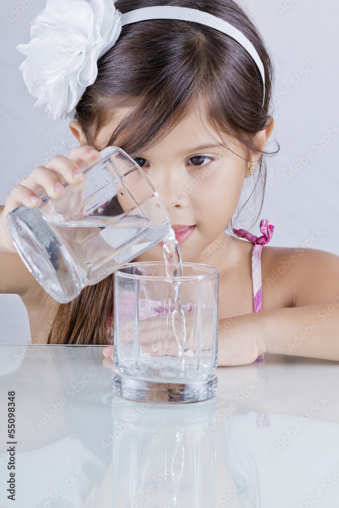 Pequeña niña vierte agua de un vaso a otro Stock Photo