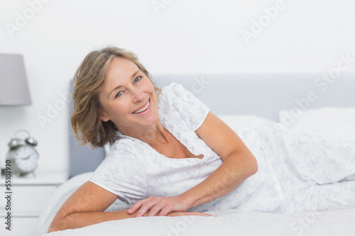 Cheerful blonde woman lying on bed