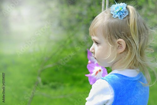 little girl on green grass in the spring in a Blue Dress