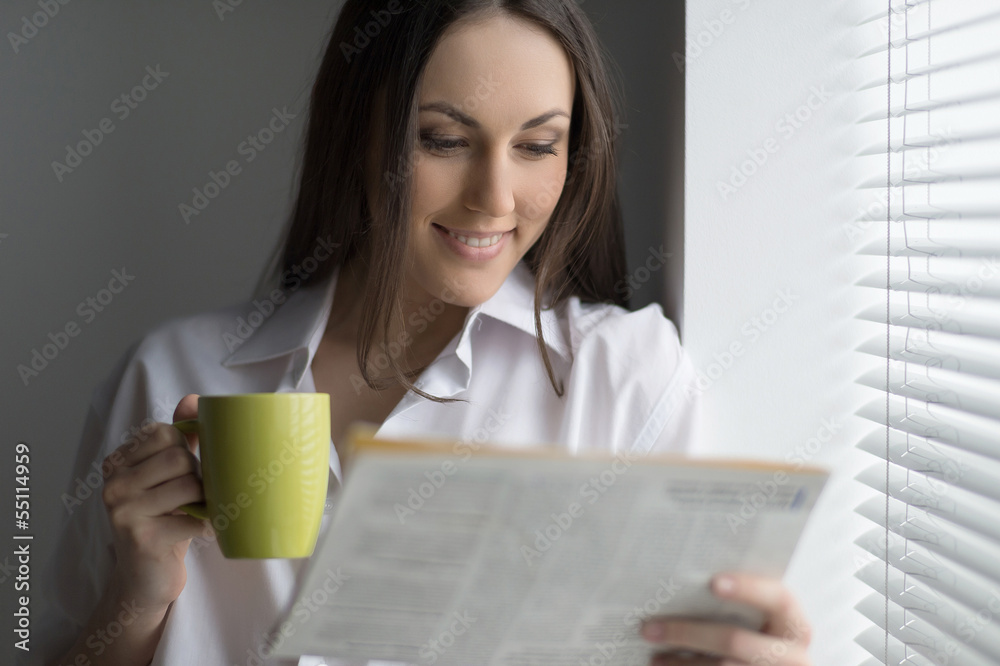 Hot coffee and fresh news. Beautiful young woman reading newspap Hot coffee and fresh news. Beautiful young woman reading newspap