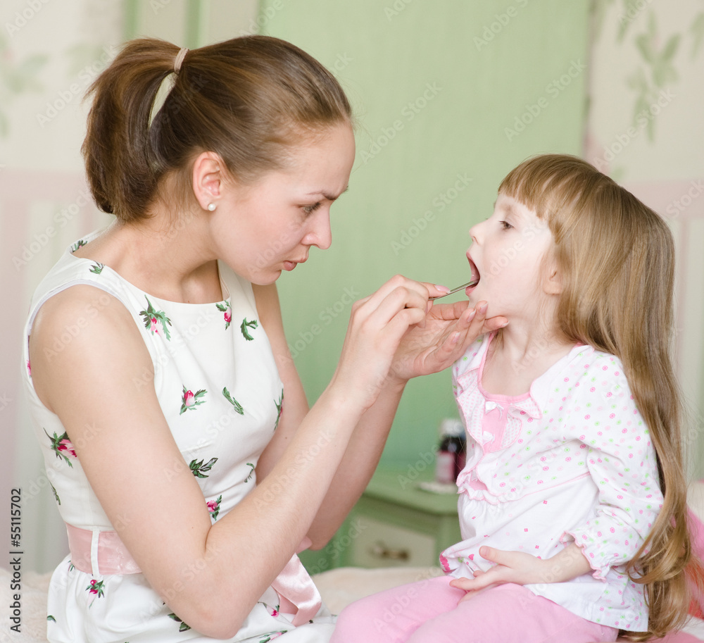 mother examining little girl's throat