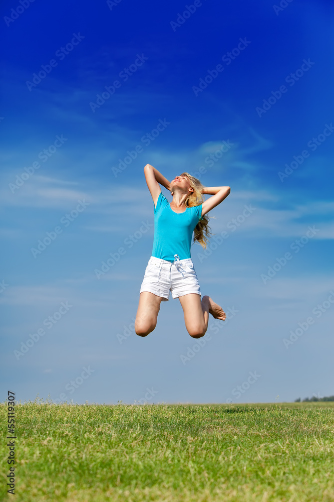 happy woman jumps in a summer green field against the blue sky.. happy woman jumps in a summer green field against the blue sky..