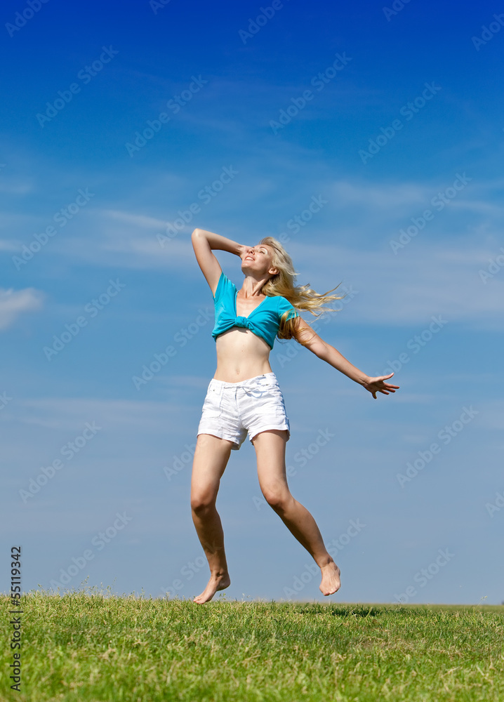 happy woman jumps in a summer green field against the blue sky.. happy woman jumps in a summer green field against the blue sky..
