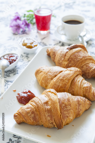 Croissants on table with jam, orange juice and coffee