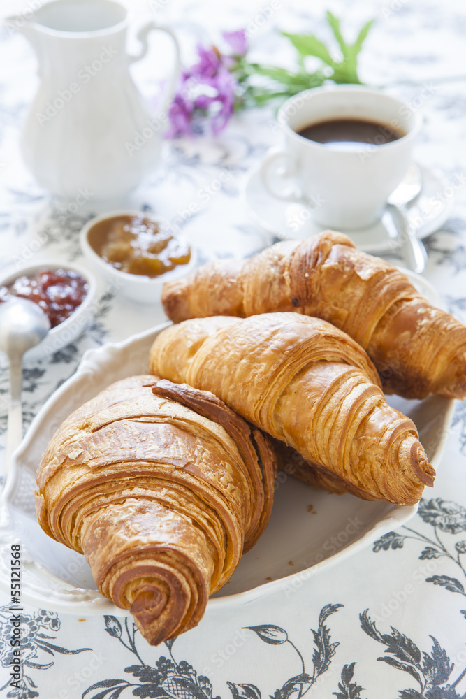 Croissants on table with jam and coffee