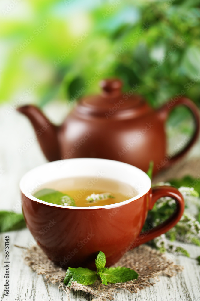 Teapot and cup of herbal tea with fresh mint flowers Teapot and cup of herbal tea with fresh mint flowers