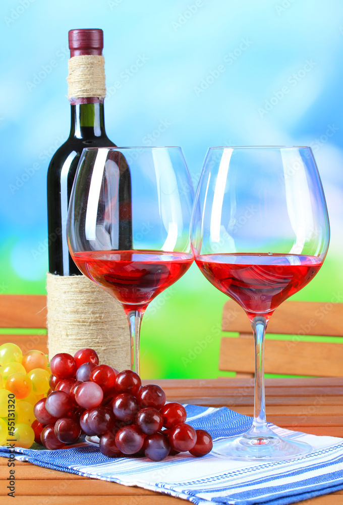 Obraz premium Glasses of wine on napkin on wooden table on nature background