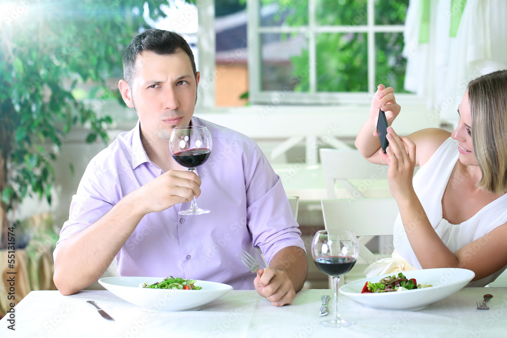Young couple taking photo with mobile phone in restaurant Young couple taking photo with mobile phone in restaurant