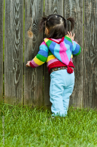 Baby toddler peeping through fence hole