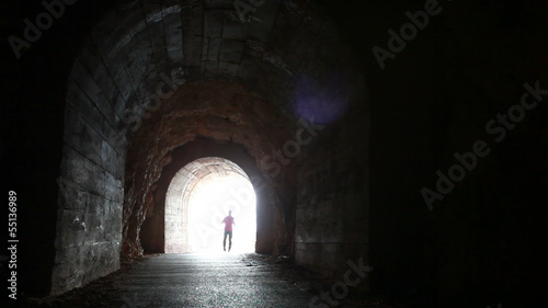 Man runs through the dark concrete tunnel