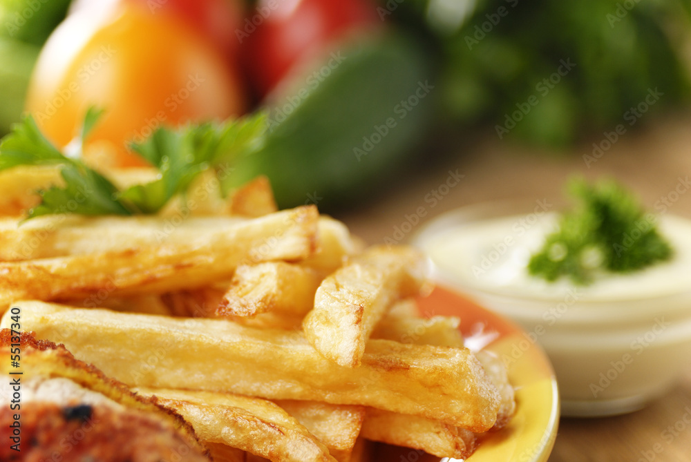 French fries and chicken on the plate on the wooden table French fries and chicken on the plate on the wooden table