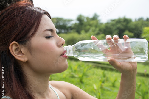 Young woman drinking water at park