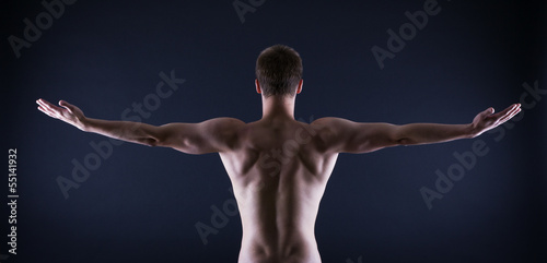 athlete stands with his back against a black background