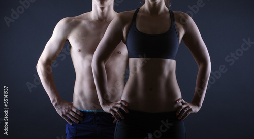 Strong man and a woman posing on a black background