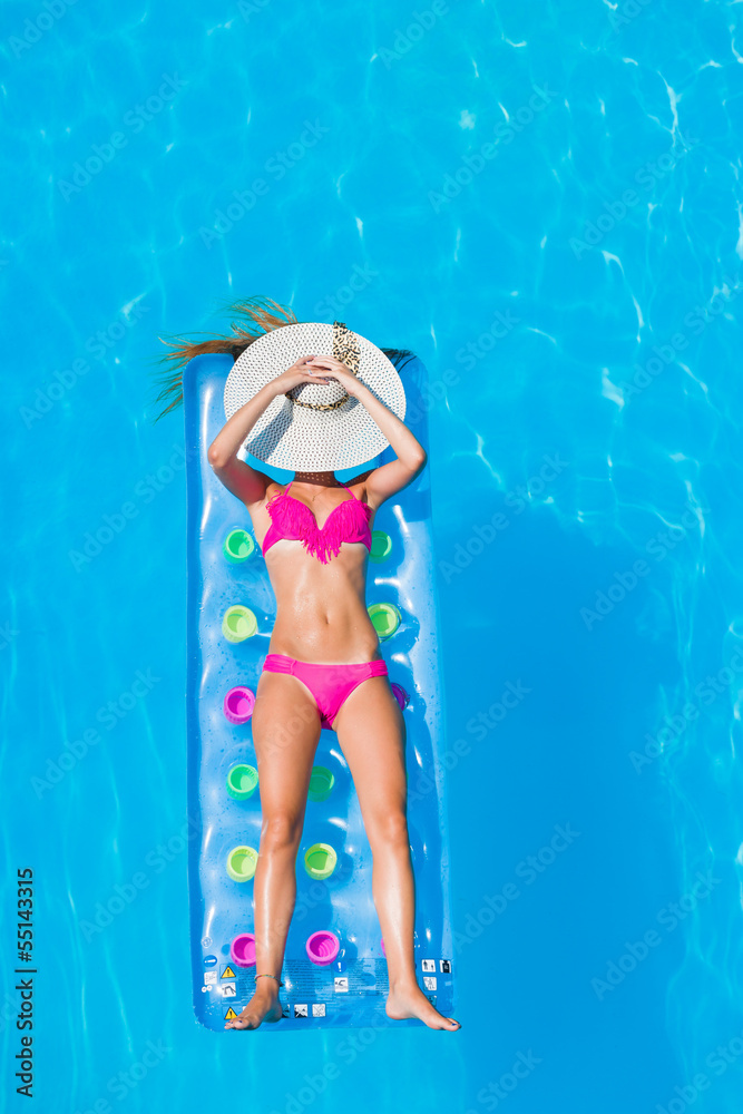 Young woman  on a lilo in the swimming pool
