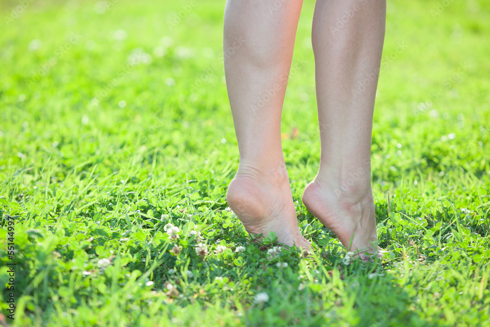 Female legs standing on tiptoe on green grass. Close up