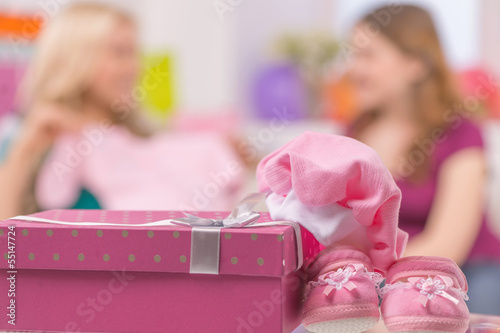 Baby shower. Young women showing baby clothes while gift box lyi photo