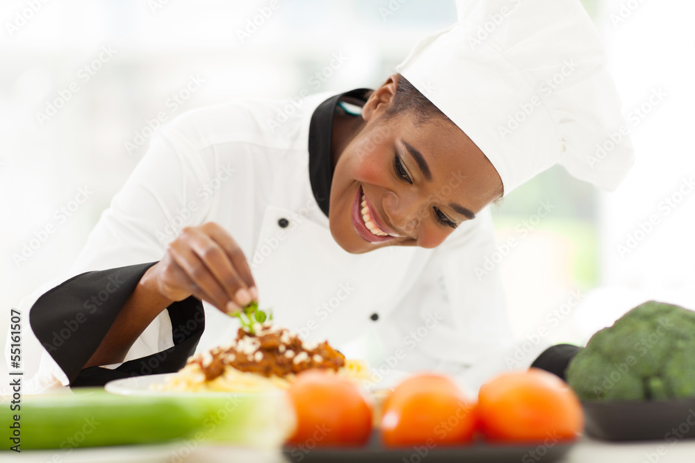 african female chef garnishing spaghetti dish