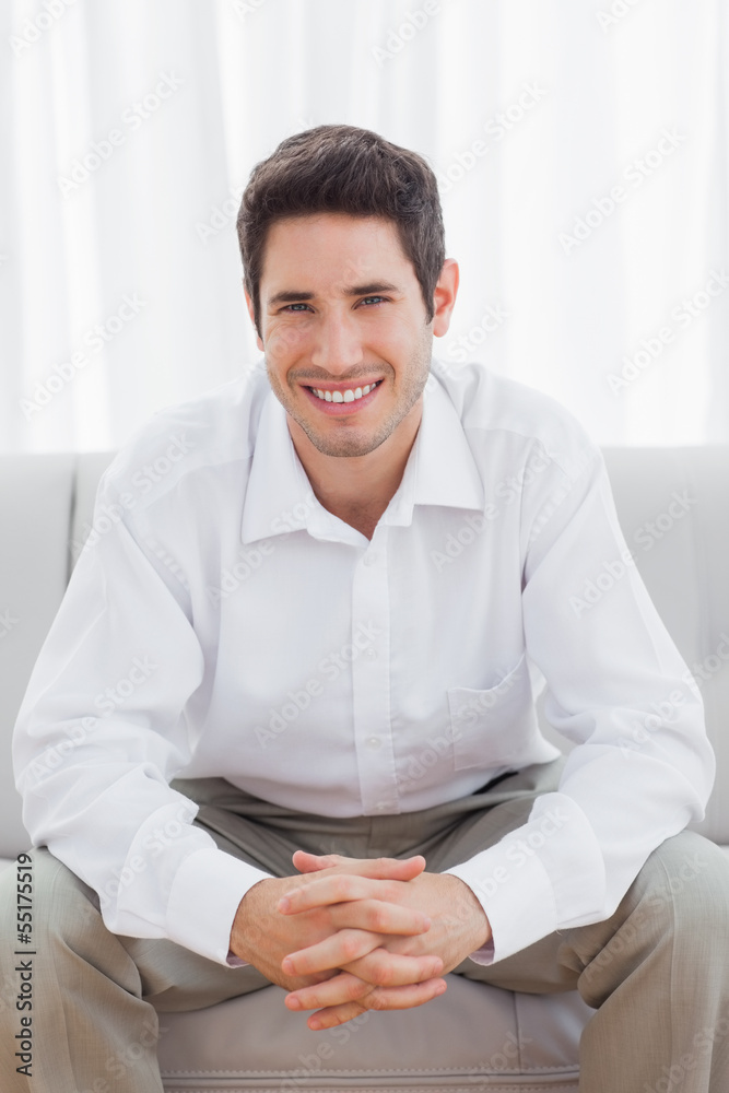 Cheerful young man sitting on sofa Cheerful young man sitting on sofa