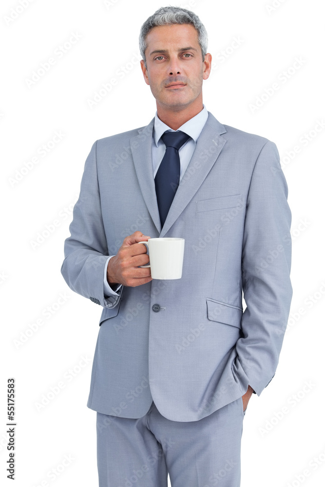 Serious businessman standing with coffee Serious businessman standing with coffee