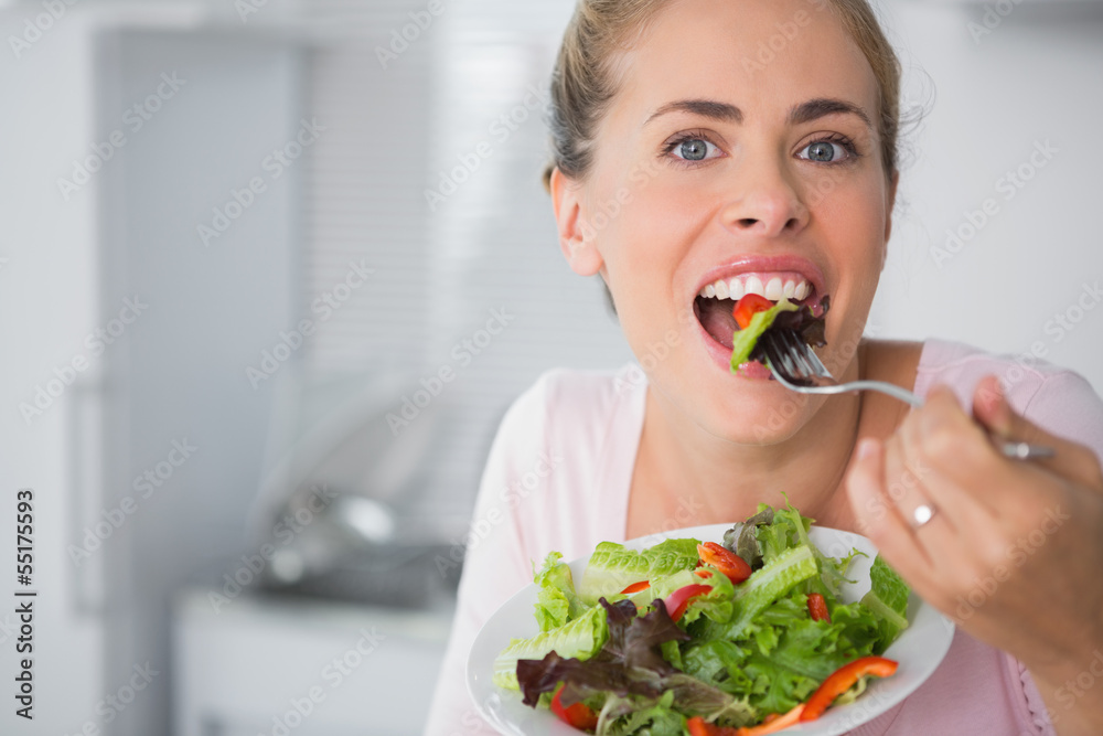 Casual blonde posing while eating salad Casual blonde posing while eating salad