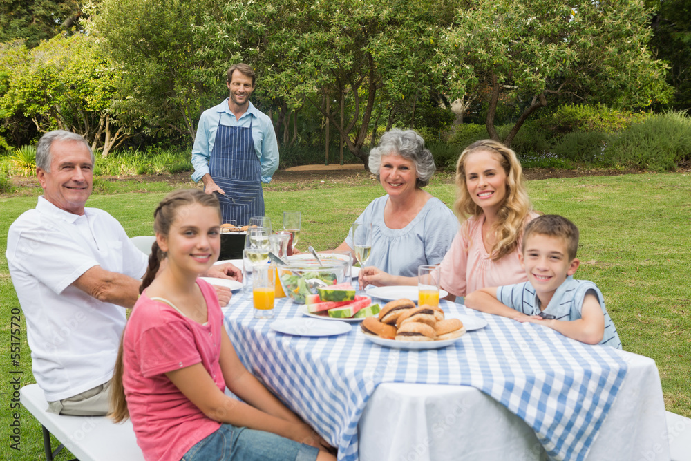 Happy extended family having a barbecue being cooked by father Happy extended family having a barbecue being cooked by father