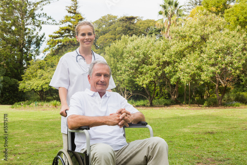 Man sitting in a wheelchair with his nurse pushing him © WavebreakmediaMicro