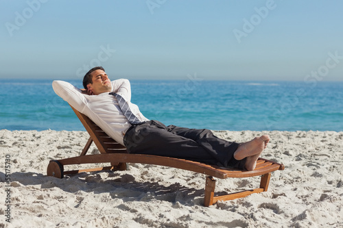 Billede på lærred Young businessman relaxing on a deck chair