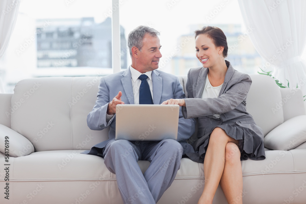 Cheerful workmates working together sitting on sofa