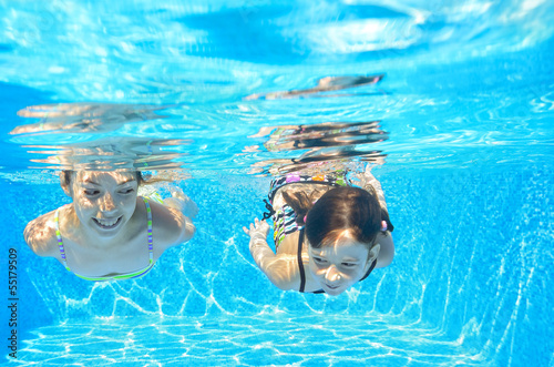Happy girls swim underwater in pool, having fun on vacation