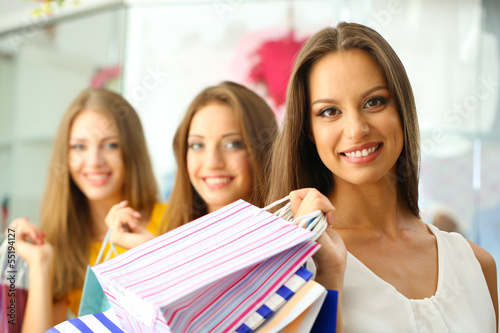Three beautiful young woman in shop with shopping bags