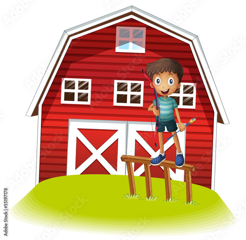 A boy standing above the fence holding an archery