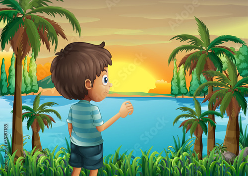 A boy watching the sunset at the riverbank