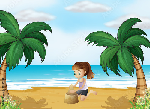A young girl forming a sand castle at the beach