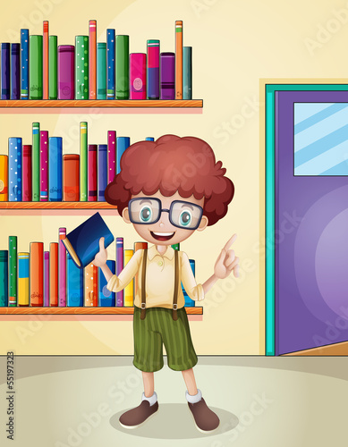 A smiling boy holding a book in front of the bookshelves