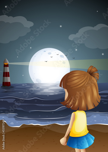 A small girl at the beach watching the lighthouse