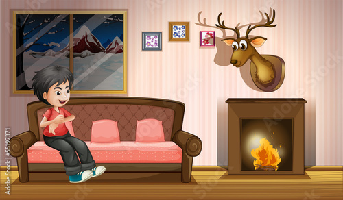 A boy sitting at the sofa near the fireplace