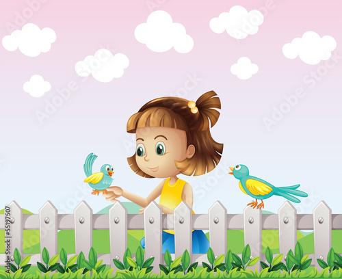 A young girl playing with the birds near the fence