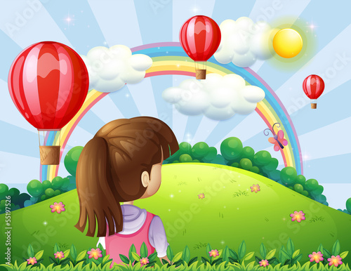 A young lady watching the floating balloons and rainbow