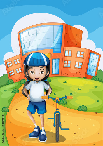 A female biker standing in front of a school building